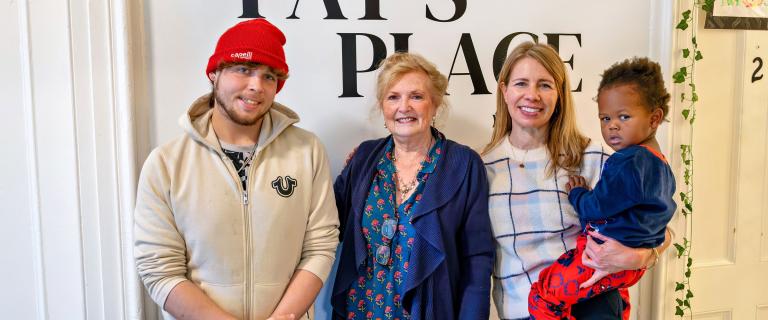 Three adults smiling for a photo while one holds a child.