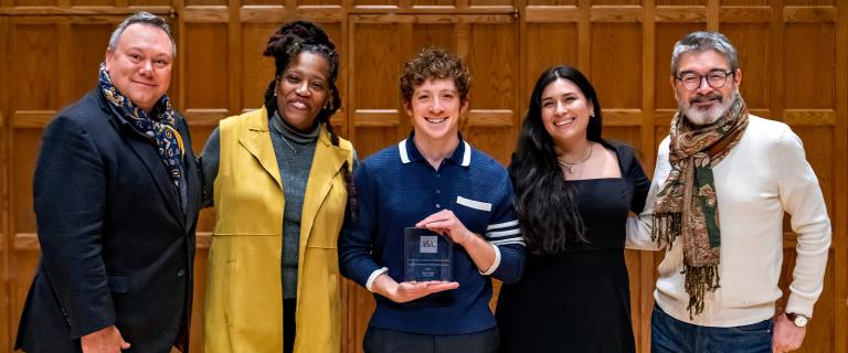 Five people smiling for the camera, with the center subject holding an award.