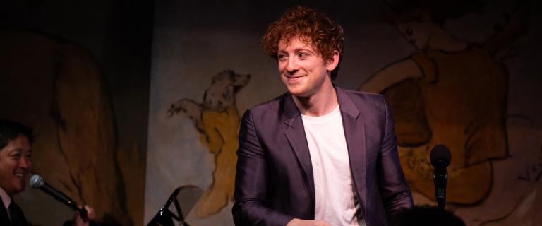 Smiling person on stage looking on.