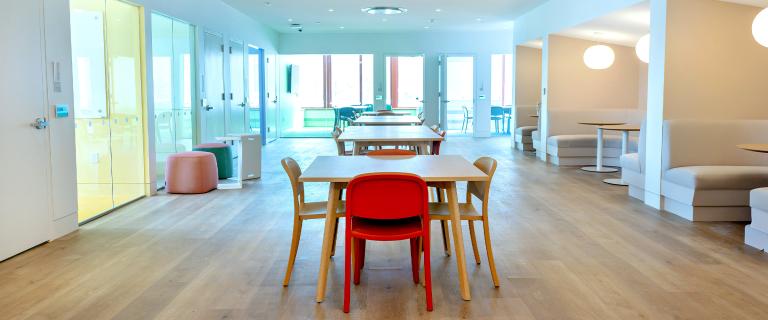 Empty table and chairs in a well lit room with windows.