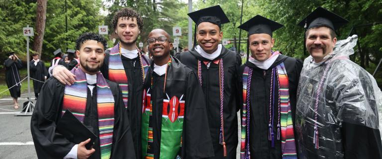 A smiling group of graduates in colorful Commencement attire.