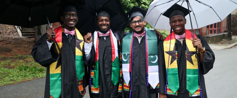 A smiling group of graduates in colorful Commencement attire.
