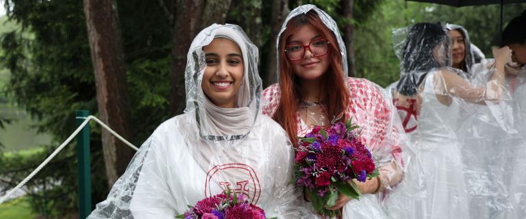 A smiling couple of graduates in rain gear.