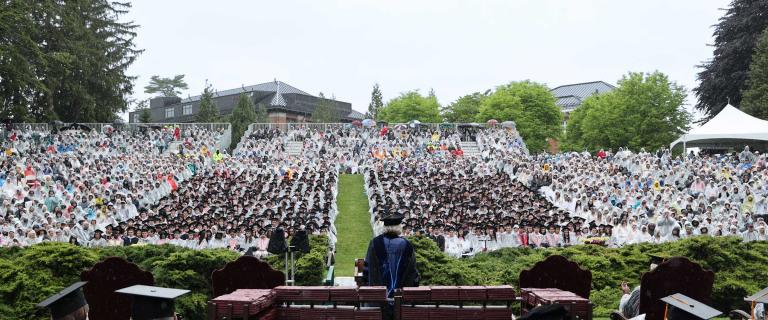 Commencement speaker addressing a large outdoor audience.