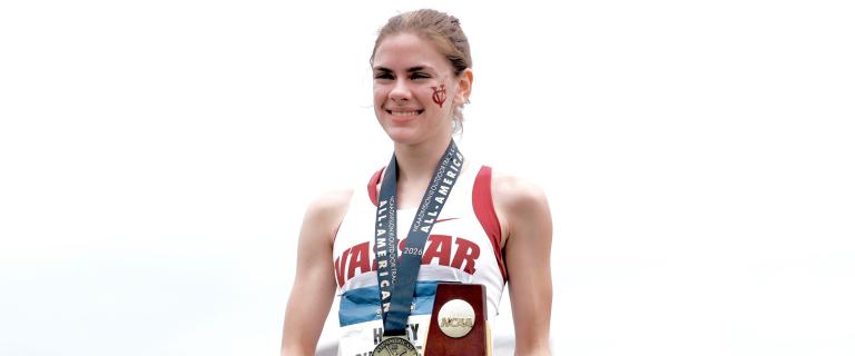 Smiling athlete standing with a medal and a trophy.