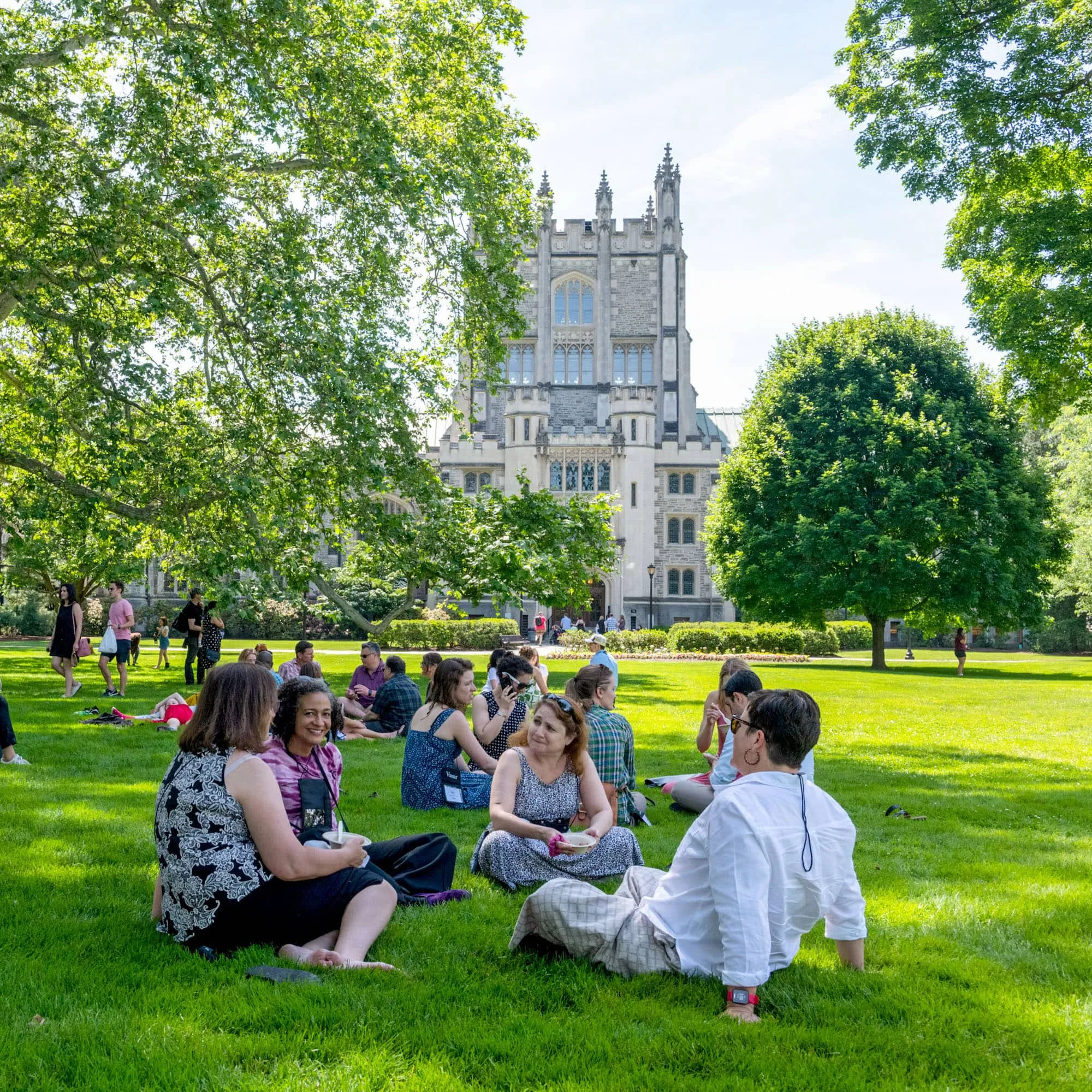 Families sitting on grass in campus center.