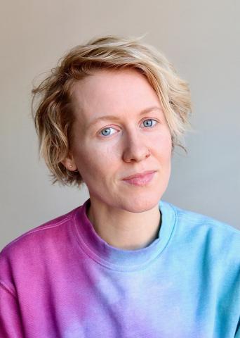 Katie Gemmill wearing a pink and blue shirt against a light background.