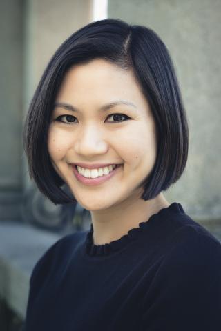 Person with black hair and a black shirt smiling in a portrait.