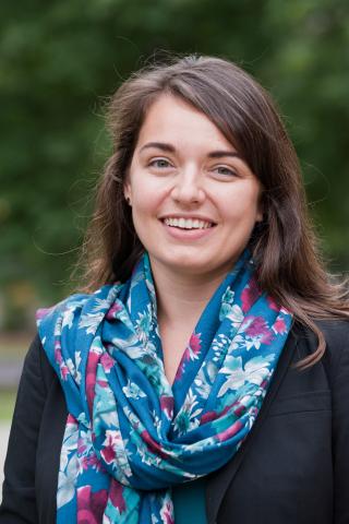 Kirsten M. Wesselhoeft wearing a black jacket and blue patterned scarf with trees in the background.