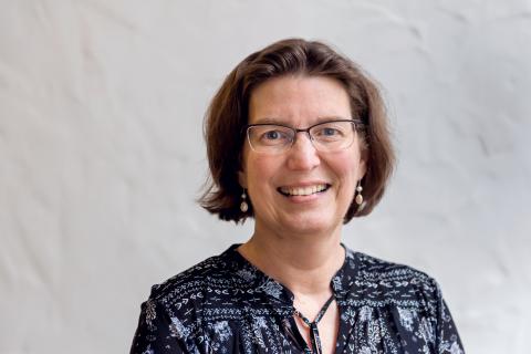 Carolyn F. Palmer wearing a black patterned shirt against a light background.