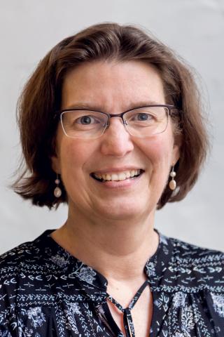 Carolyn F. Palmer wearing a black patterned shirt against a light background.