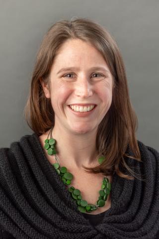 Amanda Culp wearing a black shirt and green necklace strung with multi-sized green circles.