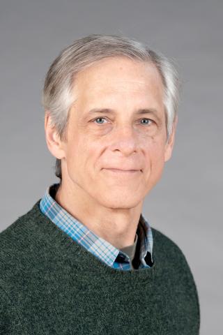 Luke Hunsberger wearing a green sweater over a blue plaid shirt.