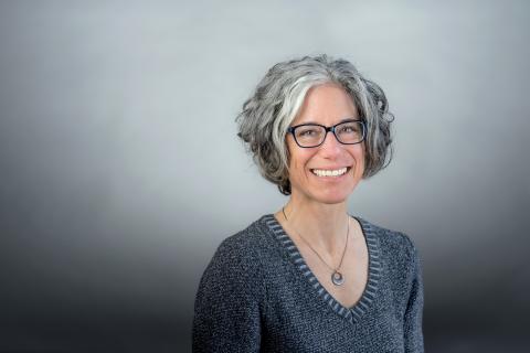 Susan G. Blickstein wearing a gray sweater and silver necklace against a gray background.