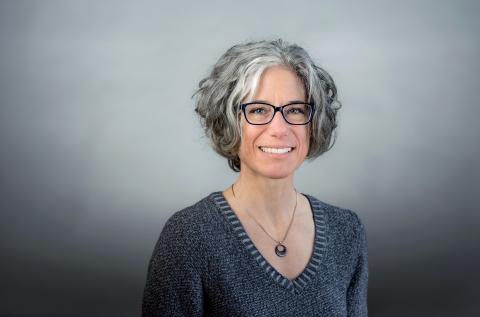 Susan G. Blickstein wearing a gray sweater and silver necklace against a gray background.