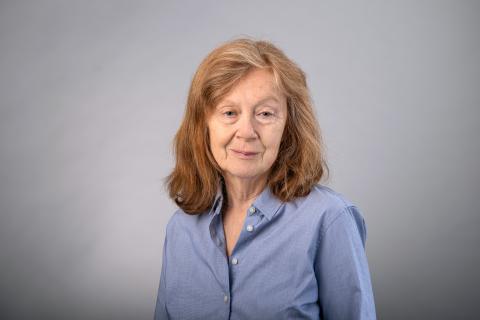 Jean M. Kane wearing a light blue collared shirt against a light gray background.