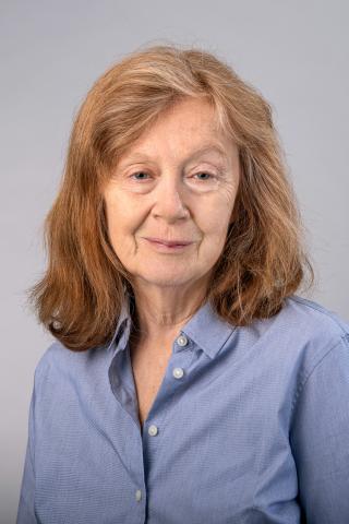 Jean M. Kane wearing a light blue collared shirt against a light gray background.