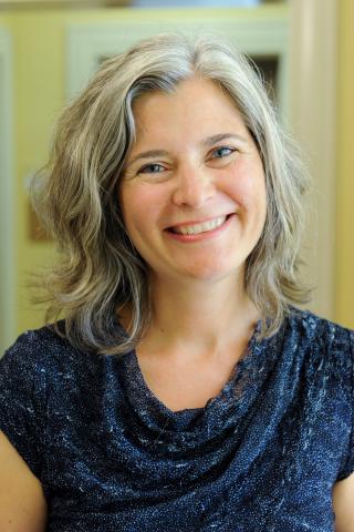 Lydia Murdoch wearing a blue shirt against a light background.