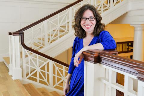 Dara N. Greenwood wearing a blue dress standing on a staircase.