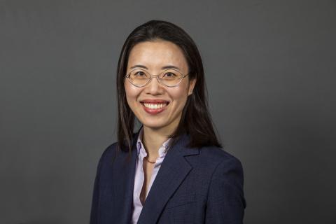 Portrait of a woman with glasses and a blue blazer smiling