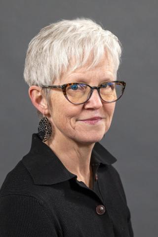 Woman with glasses, black shirt, and grey hair