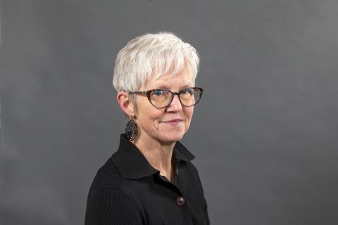 Woman with glasses, black shirt, and grey hair