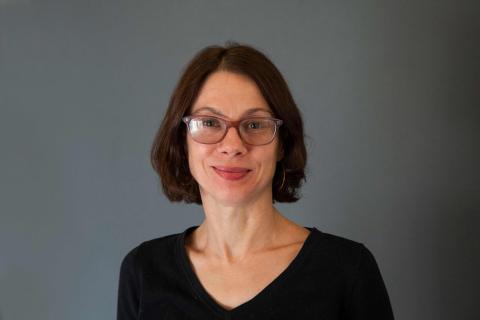 Sarah Pearlman wearing a black shirt against a gray background.