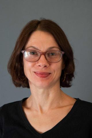 Sarah Pearlman wearing a black shirt against a gray background.