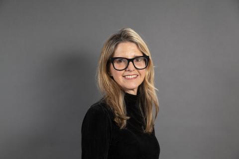 Eva Woods Peiró wearing a black shirt against a gray background.