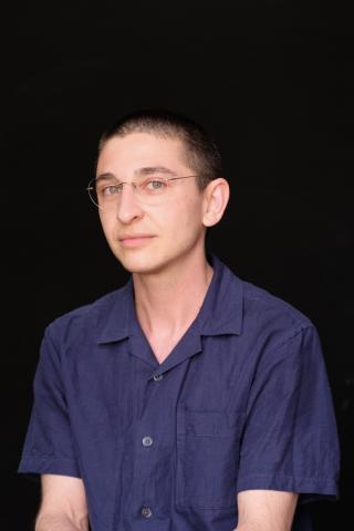 Gordon Hall wearing a blue shirt with a black background.