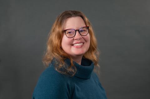 A studio portrait of a person on a dark background.
