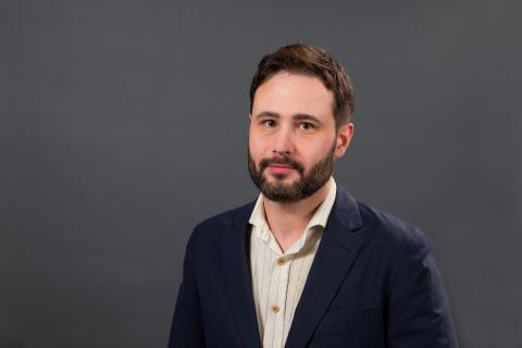 Studio portrait of a person in a suit jacket with no tie.