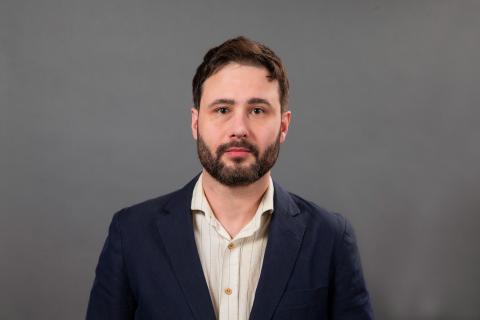 Studio portrait of a person in a suit jacket with no tie.