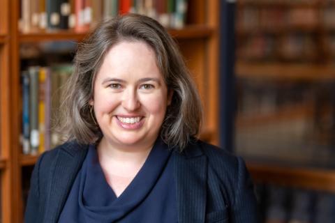 Portrait of a person with library book shelves in the background.