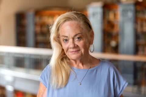 Portrait of a person with library shelves in the background.