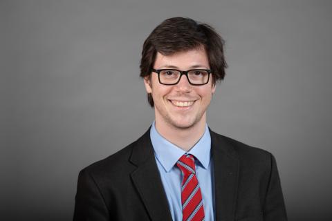 Portrait of a person with a suit, tie, and glasses.