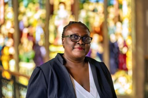 A photo of Patricia Achiro Olwoch, a person with short black hair, glasses, and a black jacket.