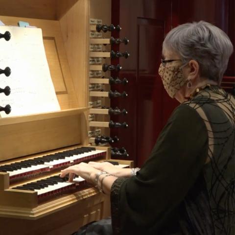 Gail Archer playing the organ with face mask on.