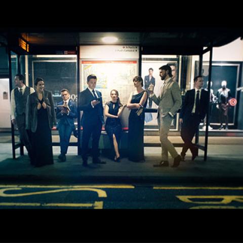 members of the vocal ensemble VOCES8 standing in an outdoor bus shelter at night