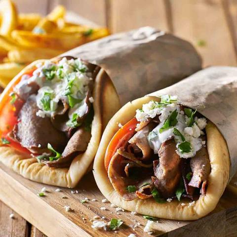 A close-up photo of Greek gyro wraps with fries.