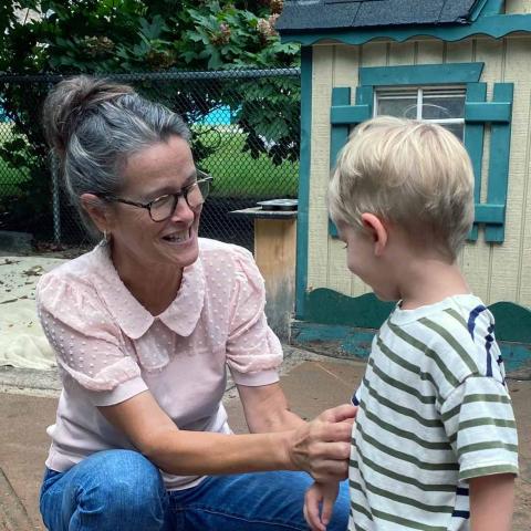 Carol Murray squatting down to speak to a toddler