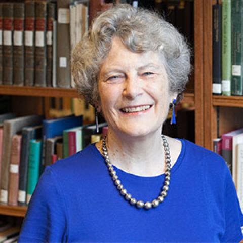 headshot of Molly Shanley smiling at the camera with a large case of books behind her.