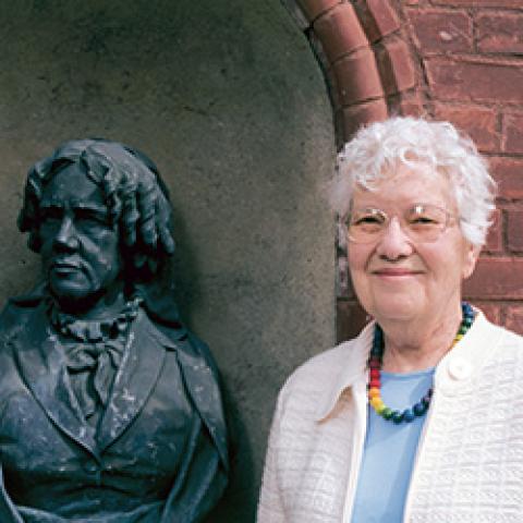 Vera Rubin standing outside Vassar's observatory next to the statue of Maria Mitchell.