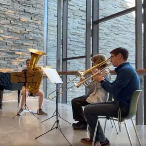 Three students playing tuba, trombone and trumpet
