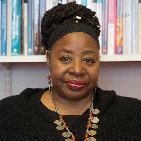 Loretta Ross seated in an office with a shelf of books behind her.
