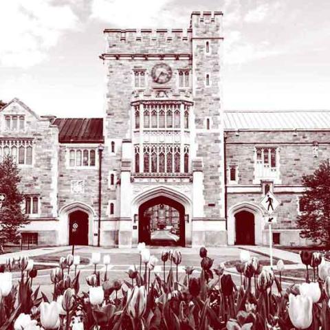 A monochrome photo of the front of the Taylor Hall Gate: a large stone building with the entrance to campus