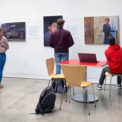 People looking at artworks on a wall with their backs facing the camera