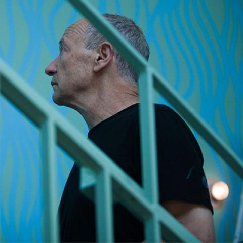 profile view of Harry Roseman as seen through the bars of a staircase railing.