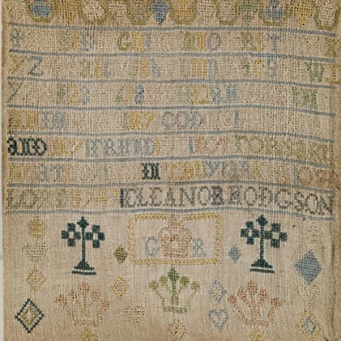 An off-white square of fabric embroidered with colored threads forming the alphabet, the maker's name, and assorted crown imagery.