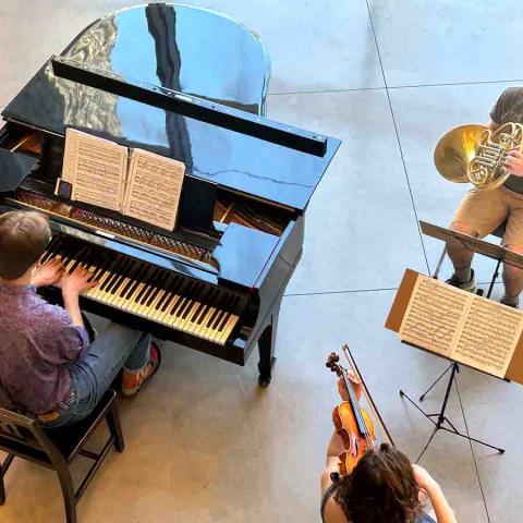 Aerial view of man at the piano performing with a violinist and a horn player